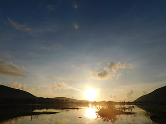 Sunset over a lake with hills and clouds
