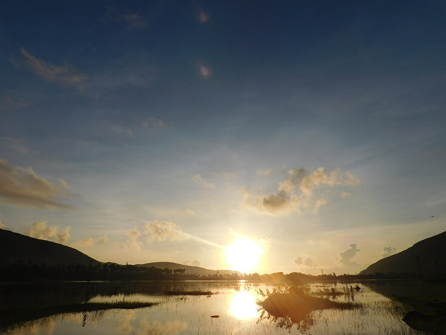 Sunset over a lake with hills and clouds