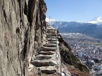 Steep stone steps carved into a cliffside overlooking a valley town