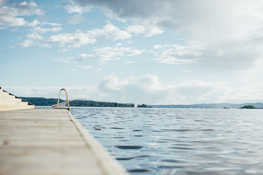 Serene Lake View from Wooden Dock with Sailboats