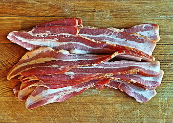Raw bacon strips on wooden cutting board