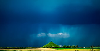 Dramatic Blue Storm Over Green Hill And Rural Fields