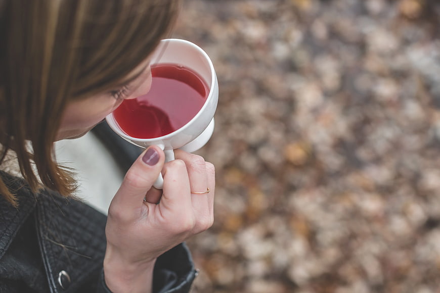 Woman Sipping Red Tea in Autumn Park