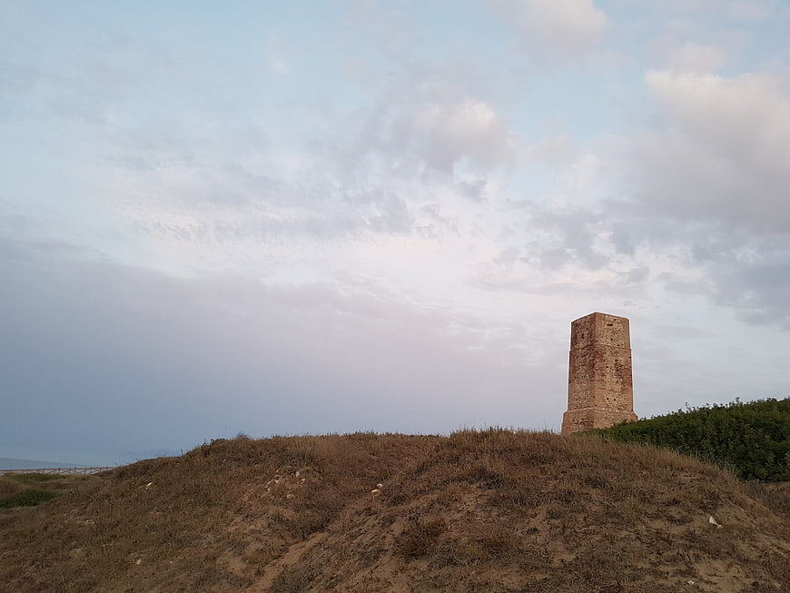 Ancient brick tower on grassy hill against cloudy sky