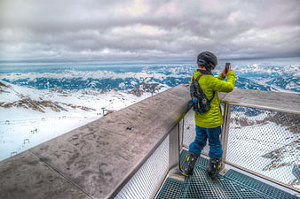 Skier taking photo of snowy mountain landscape from observation deck