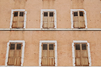 Symmetrical wooden shutters on peach building facade