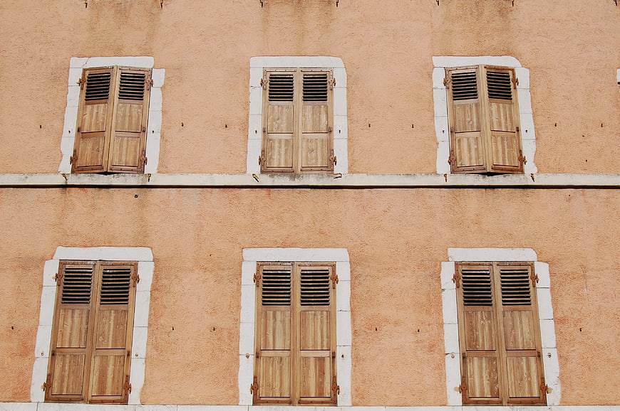 Symmetrical wooden shutters on peach building facade