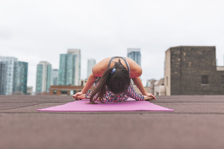 Woman doing yoga on rooftop with city skyline background