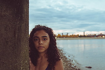 Serious Woman Portrait Leaning Against Tree by Lake