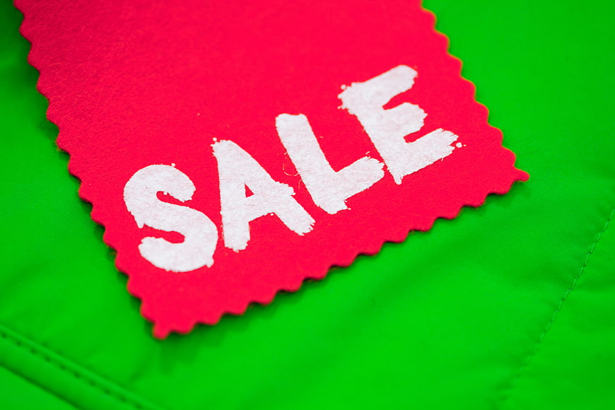 Red Sale Sticker on Green Jacket Background