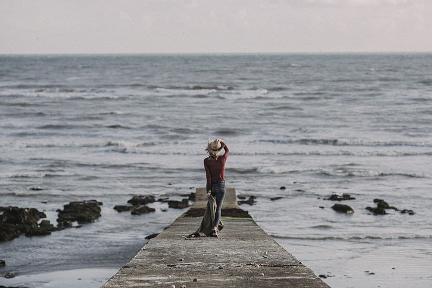 Woman Standing on Wooden Pier Looking at Ocean