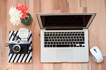 Flat lay workspace with laptop, camera, and flowers