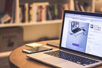Laptop and smartphone on wooden desk with bookshelf background