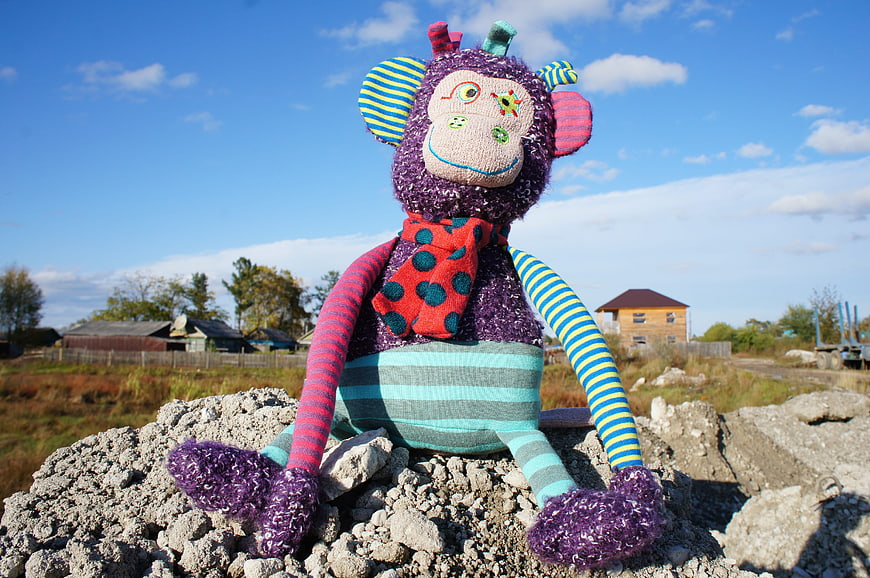 Colorful Knitted Monkey Toy on Rocks Outdoors