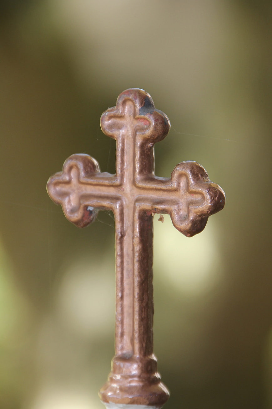 Close-up of weathered brown metal cross finial