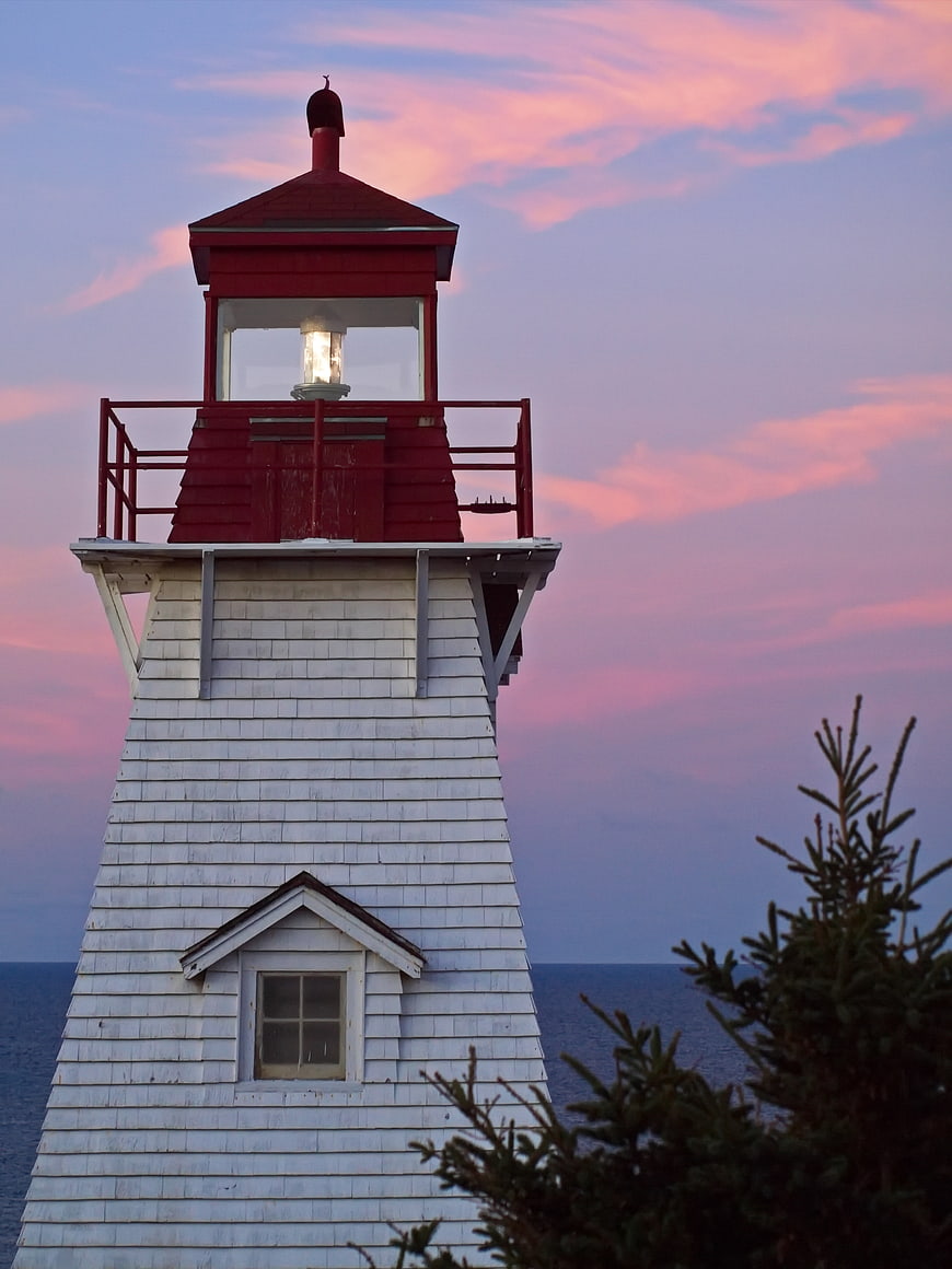 Red and White Lighthouse Against Pink Sunset Sky