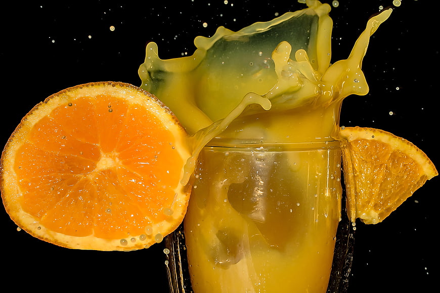 Dynamic Orange Juice Splash With Fresh Citrus Slices In Glass
