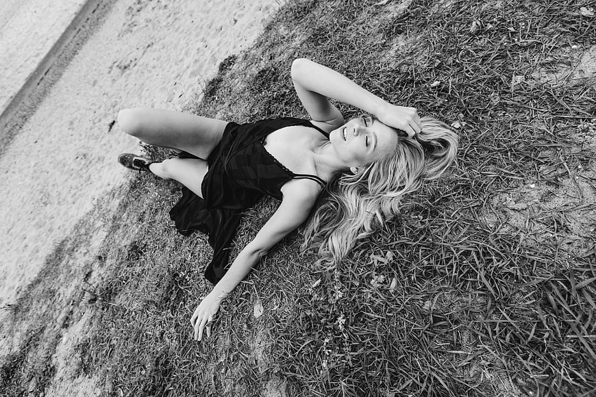 High angle black and white photo of woman lying on grass