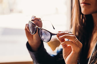 Woman holding sunglasses near window