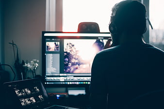 Video Editor Working on Laptop and Monitor with Headphones