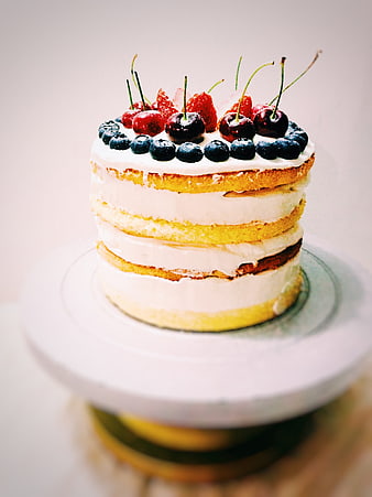Rustic Naked Layer Cake Topped With Fresh Cherries, Strawberries, And Blueberries