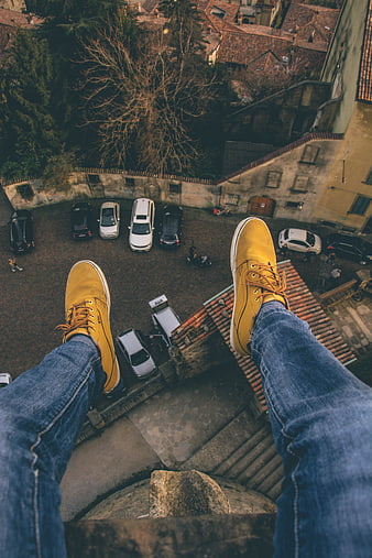 Yellow sneakers dangling over European city rooftop view