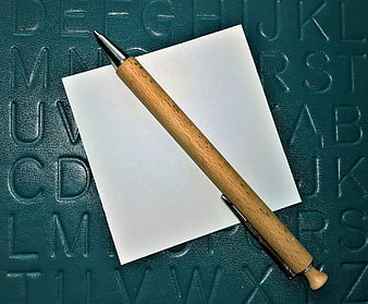 Wooden Pen On Blank Note Over Embossed Alphabet Background