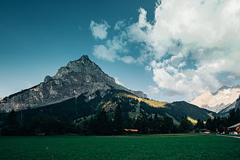 Alpine Mountain Peak With Green Pasture And Dramatic Clouds