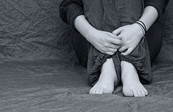 Black and white photo of person hugging knees in despair