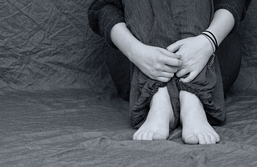 Black and white photo of person hugging knees in despair