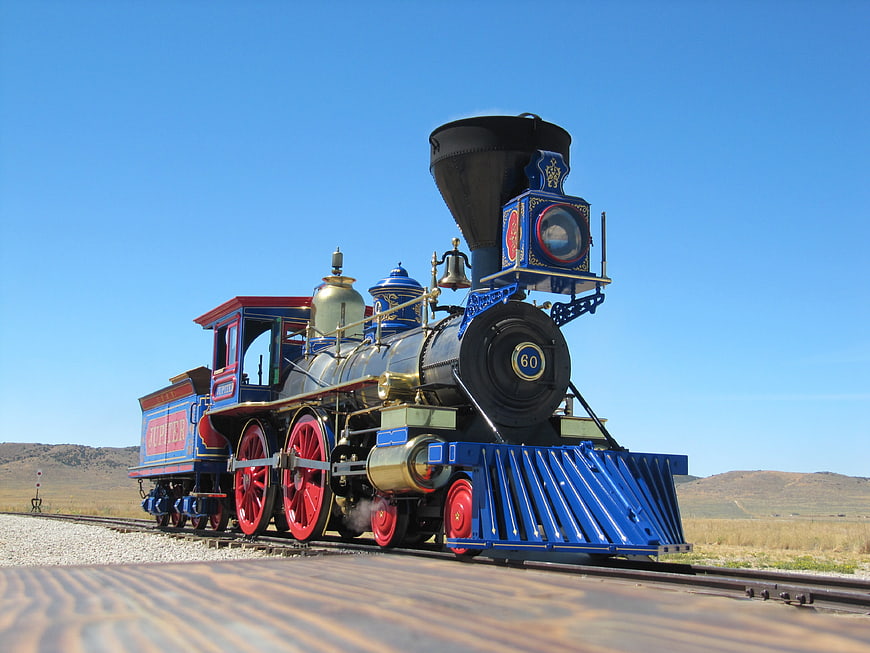 Vintage Blue and Red Steam Locomotive on Desert Railroad Tracks