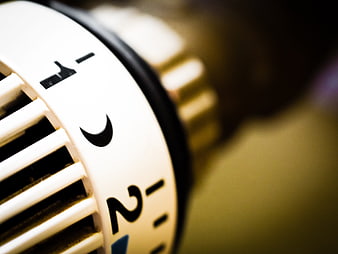 Close-up of white thermostat dial with temperature settings