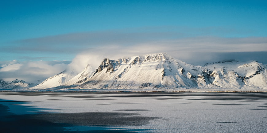 Snow-Covered Mountain Range Over Frozen Lake in Winter