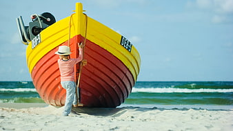 Child Climbing Colorful Fishing Boat on Sandy Beach