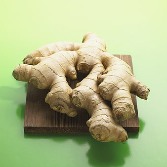 Fresh Ginger Roots on Wooden Board Against Green Background