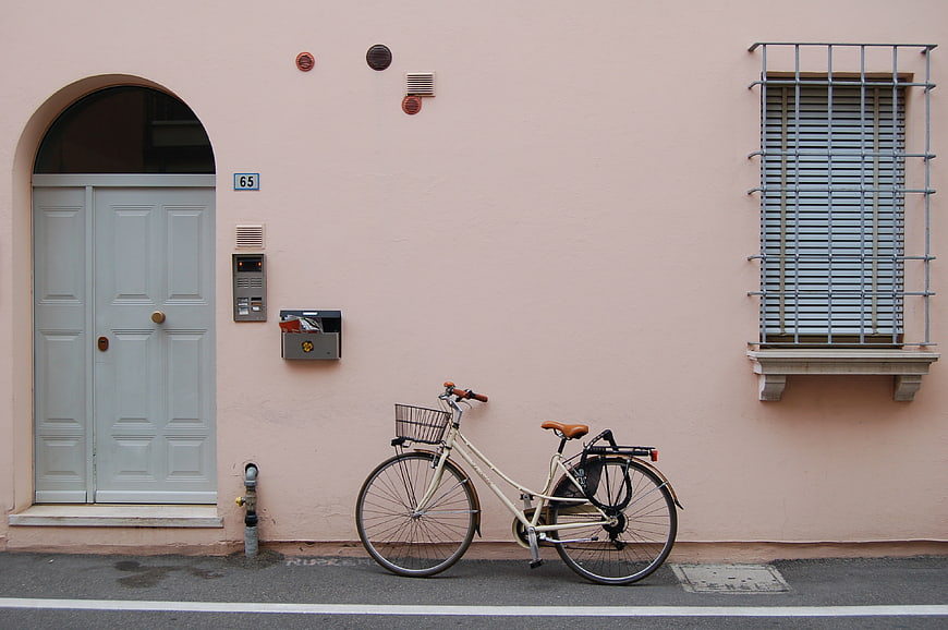 Vintage bicycle parked against pastel pink building facade