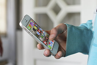 Hand holding white smartphone with app icons on screen
