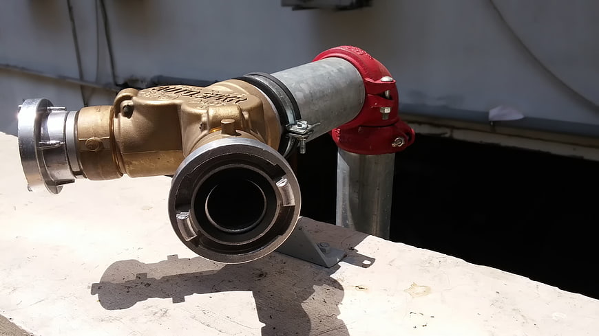 Brass Fire Pump with Red Pipe Connection on Concrete