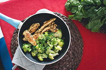 Top view of pan-fried chicken and broccoli on red table