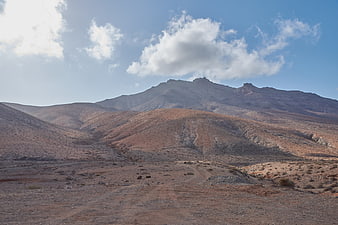 Arid volcanic landscape with rugged mountains and blue sky