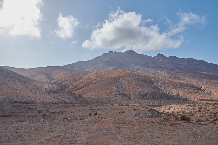 Arid volcanic landscape with rugged mountains and blue sky