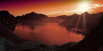 Dramatic Sunset Over Mountain Lake with Sun Rays