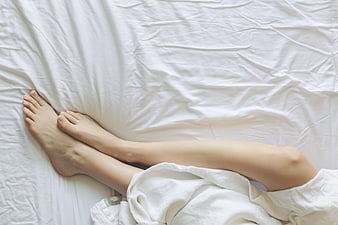 Relaxed bare feet on white bed sheets morning