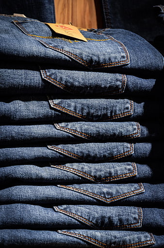 Stack of folded blue jeans with orange stitching