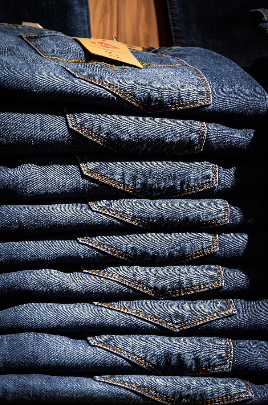 Stack of folded blue jeans with orange stitching