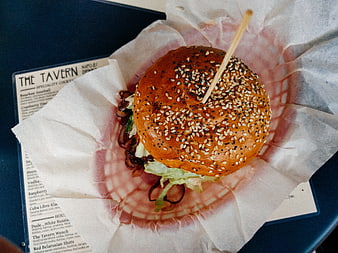 Overhead view of gourmet burger with sesame bun on parchment paper