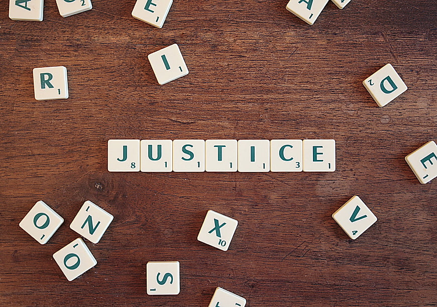 Scrabble Tiles Spelling Justice on Wooden Table