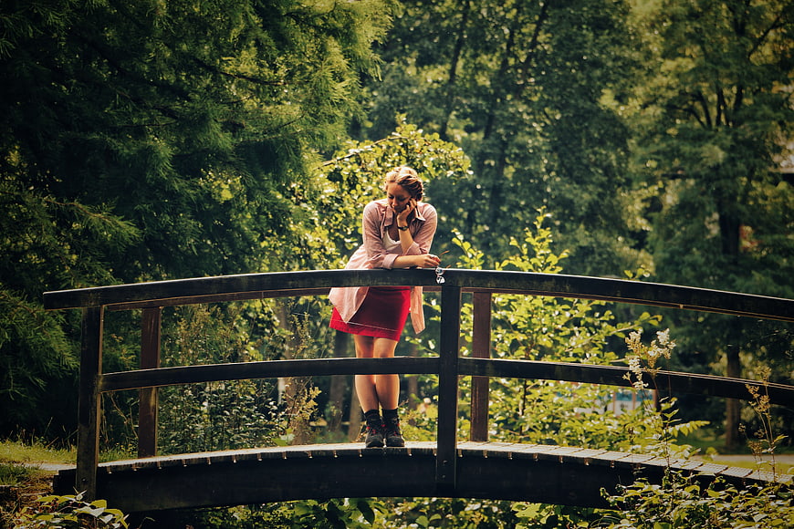 Woman talking on phone on wooden bridge in forest