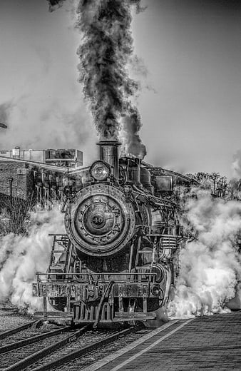 Vintage Steam Locomotive Billowing Smoke on Railroad Tracks