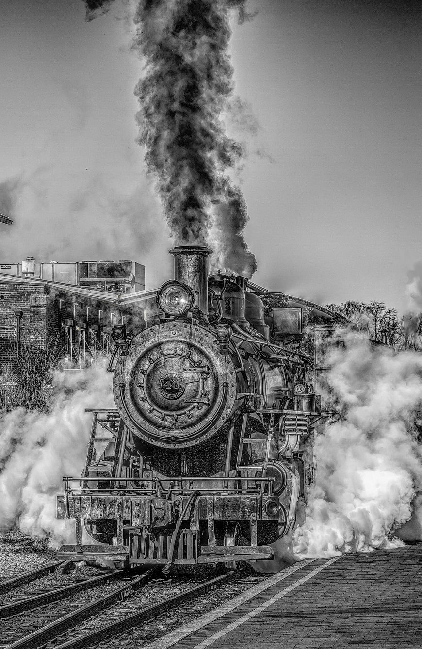 Vintage Steam Locomotive Billowing Smoke on Railroad Tracks